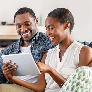A cheerful couple uses their tablet to review their Health Savings Account on Patelco Online.